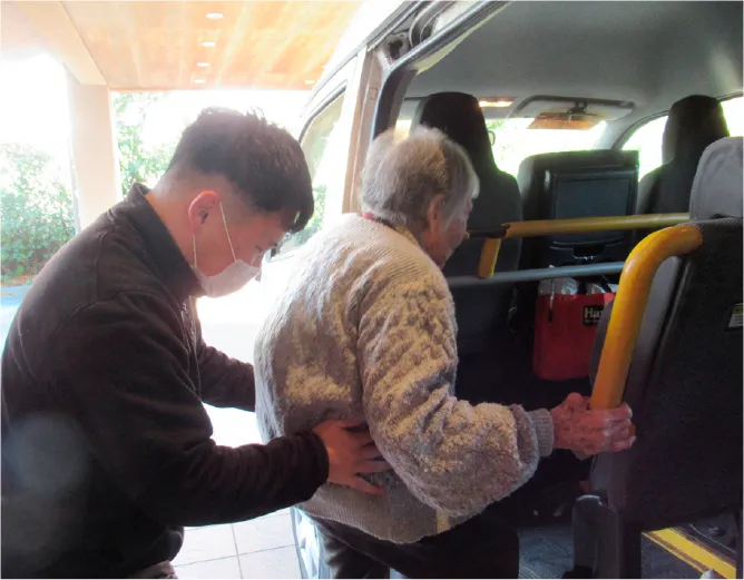 職員が車椅子の高齢者を福祉車両へ丁寧に介助している様子