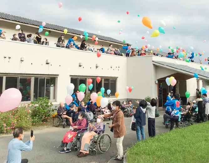 利用者と職員が風船を空に飛ばしている様子