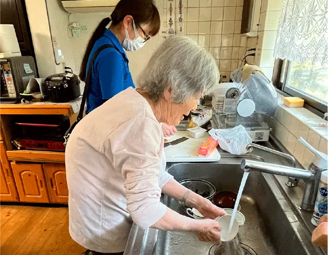台所で食器を洗う高齢者と介護士