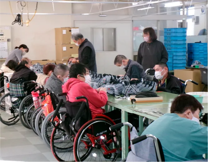作業場で働く車椅子の利用者と職員たち