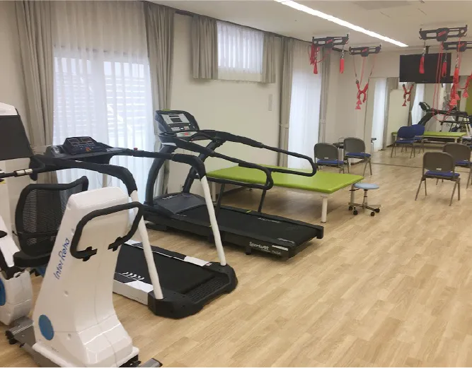トレーニング機器が並ぶ明るいリハビリ室